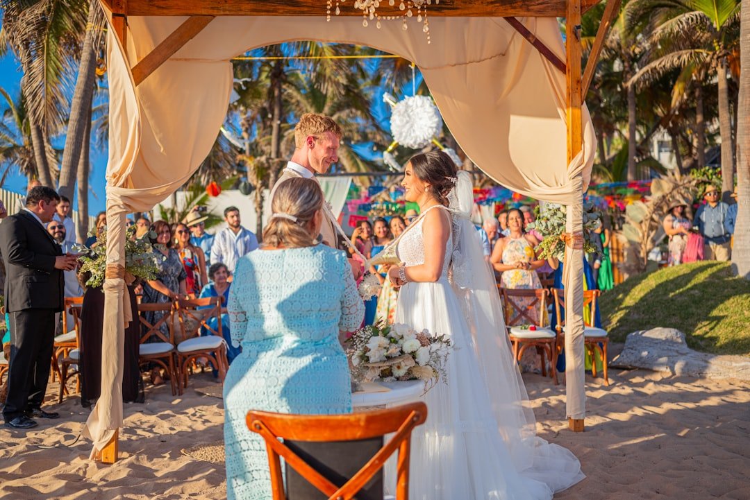 Wedding ceremony on a sandy beach with guests watching guests.