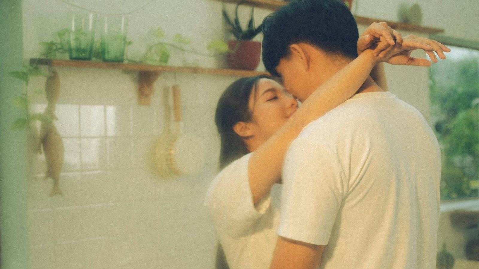 Young couple embracing in a warm and cozy kitchen setting, capturing a tender moment of love.